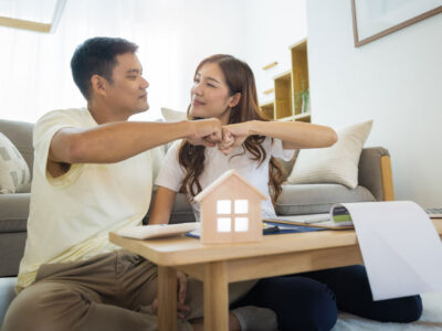 Asian couple in their living room giving a hand pump to each other.