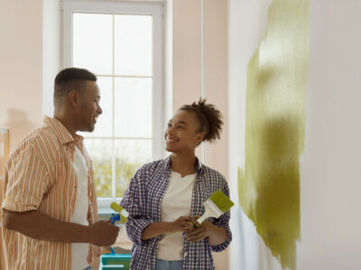 African man and woman painting a wall in their house.