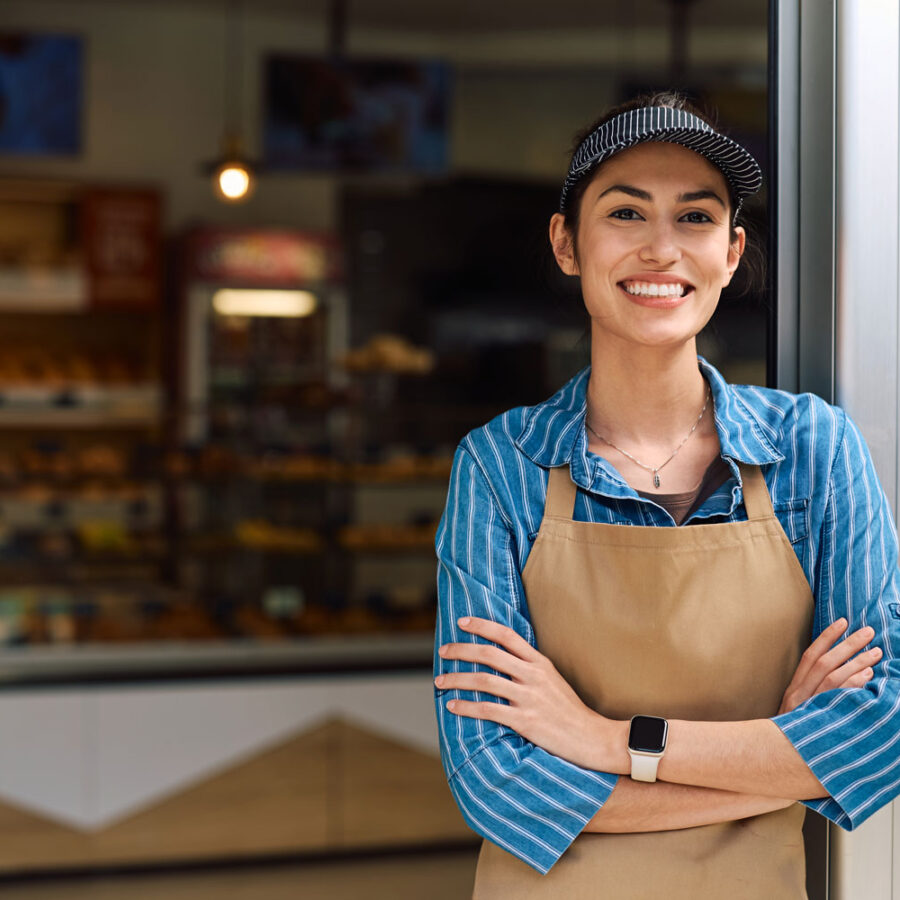 Woman with arm crossed with nice smile in front of storefront for Commercial Escrow.
